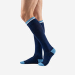 Angled view of custom navy blue soccer socks with sky blue cuff stripe and reinforced heel zone on adult male model