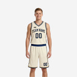 Cream and navy reverse side of the reversible basketball uniform showing navy arched team name, front number 00, and cream matching shorts with navy trim