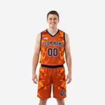Orange and blue basketball uniforms in digital camo with navy V-neck and team name arced across the chest, front view of the full two-piece set