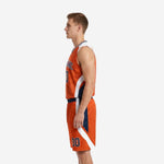 Side view of orange basketball uniform showing curved white jersey side panel and navy accent insert on the matching shorts outer leg
