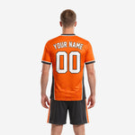 Close detail of custom orange soccer jersey with charcoal collar, white cuff trim and hexagon texture