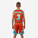Side view of orange youth basketball uniform set showing teal armhole binding and wave detail on shorts leg