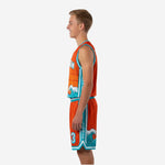 Front view of orange and teal youth basketball uniform set with large wave graphic on jersey and shorts leg