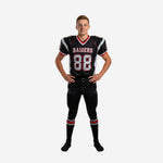 Personalized youth football uniforms in black with silver shoulder panels, red trim V-neck collar, and silver front number 88 outlined in red - full set front view