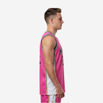 Front view of custom pink basketball jersey designs showing arched YOURTEAM name and number 23 in navy and gold on a solid pink body with white side panels