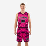 Pink basketball uniforms in digital camo sublimation showing full two-piece set with hot pink and deep purple jersey and matching shorts, front view on male model