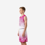 Side view of pink youth basketball uniform showing halftone fade on the jersey and matching shorts with pink hem band