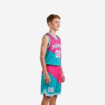 Front view of pink youth basketball uniforms showing V-neck teal binding, arched team name in white, and front number on hot pink and teal two-piece set
