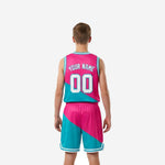 Opposite side view of custom pink youth basketball uniforms showing teal armhole binding, diagonal panel seam, and matching shorts side split with chevron trim