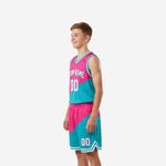 Side view of pink and teal youth basketball uniform set showing diagonal color split across jersey body and shorts panel with white hem binding detail