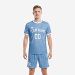 Men's plain soccer uniforms in powder blue with white trim, full kit front view showing team name and number on custom sublimated jersey and matching shorts