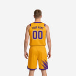 Opposite side view of gold reversible basketball uniform showing purple contrast V-neck trim and diagonal brush-stroke pattern on the shorts side panel