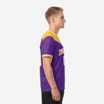 Side view of men's purple and athletic gold chevron soccer jersey showing short sleeve cuff band and sublimated panel construction