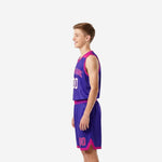 Side view of purple youth basketball uniform set showing pink armhole binding and curved pink panel on jersey and shorts
