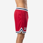 Side view of custom red basketball shorts showing navy and white ribbed waistband trim and chevron side split at hem