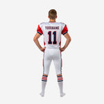 Back view of custom red and white youth football uniforms showing back player number on red shoulder panel area and white pant with red and navy side stripe visible from sideline