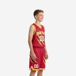 Red and gold youth basketball uniform set side view showing claw graphic continuing across the shorts leg and gold hem band