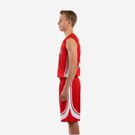 Side view of red youth basketball uniform showing white curved side panel running from jersey armhole down through the shorts sweep arc design