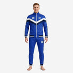 Men's royal blue soccer tracksuit with navy and white chevron chest panel, double stripe sleeves, and matching tapered pants - front view