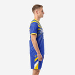 Side view of royal blue and gold soccer kit showing sunburst jersey and chevron shorts panels, full uniform set