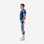 Side view of royal blue and white youth football uniform showing black jersey side panel and blue black outer leg stripe on white pants from hip to calf