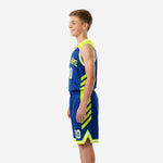 Side view of custom youth team basketball uniform showing neon yellow-green diagonal chevrons running down the jersey and shorts outer leg in royal blue