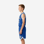 Side view of royal blue youth basketball uniform showing white armhole binding on jersey and white hem band with V-notch split on matching shorts