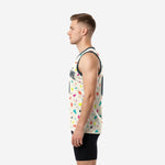 Side view of cream sublimated basketball jersey showing multicolor geometric scatter pattern and dark charcoal armhole binding on a male model
