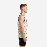 Male model wearing a cream custom sublimated basketball jersey with full-body confetti geometric pattern in teal, coral, yellow, magenta, and navy with charcoal armhole binding