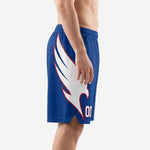 Royal blue custom sublimated basketball shorts with white wing graphic and crimson outline, front view showing elastic waistband and drawcord detail on male model