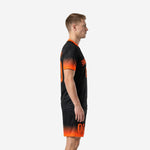 Side view of custom black soccer uniforms showing Athletic Orange gradient fade from cuffs upward into Jet Black body, men's full kit