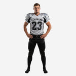 Custom sublimated football uniform sets in white and black - front view showing V-neck jersey with team name, number 23, and black side panels with full-length black pants