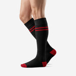 Red and black striped soccer socks with ribbed cuff and red contrast heel, angled view on male model