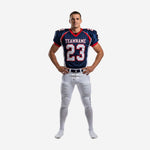 Custom tackle football uniforms in navy blue and white with red trim - front view showing team name, front number 23, and curved white side panels on jersey with matching white pants and navy leg stripe