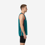 Front view of custom teal basketball jerseys showing coral armhole binding, vertical side stripe, and white arched team name lettering on male model