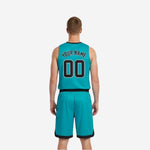 Side view of teal reversible basketball jersey with black armhole binding and black trim on matching shorts