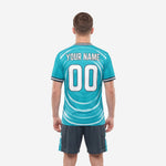 Close-up detail of teal vintage soccer jersey with white wave graphic and charcoal tipped crew collar