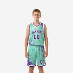 Teal youth basketball uniforms with purple dot-burst pattern, V-neck binding, and white trim - front and back view of full jersey and shorts set