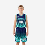 Teal youth basketball uniforms with navy flame sublimation print, V-neck jersey and matching shorts, front view, player wearing full set