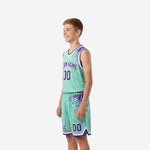 Side view of teal youth basketball uniform set showing dot-burst pattern cascading from shoulder to shorts hem with white contrast trim