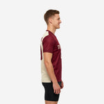 Left side view of a custom red soccer training jersey showing the vertical maroon and cream colorblock split and contrast sleeve cuff trim