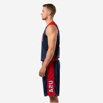 Side view of men's custom basketball uniforms showing red armhole binding on navy jersey and full-length red side panel on navy basketball shorts with USA text