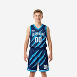 V neck youth basketball uniforms in navy and cyan with diagonal claw-mark slash pattern, sleeveless jersey and matching shorts shown on youth boy model, front view