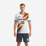 Men's white soccer uniform with charcoal shorts featuring crimson and gold diagonal splash sublimation print - front view