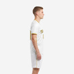 White and gold soccer kit left side view showing gold side stripe detail on jersey and shorts