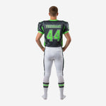 Left side view of custom white youth football uniforms in charcoal and neon green showing sleeve number and matching pant stripe alignment