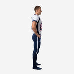 Side view of men's wholesale American football uniform showing navy curved jersey side panel, set-in sleeve with navy binding, and navy pants with white outer-leg stripe