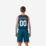 Opposite side view of teal youth basketball uniform package showing coral armhole binding and shorts side split accent