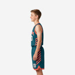 Side view of teal and coral youth basketball uniform showing diagonal slash accent on jersey and shorts leg panel