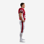 Side view of custom youth football uniform in red and white showing curved white shoulder panel, sleeve number 23, and full-length red pant stripe on white pants